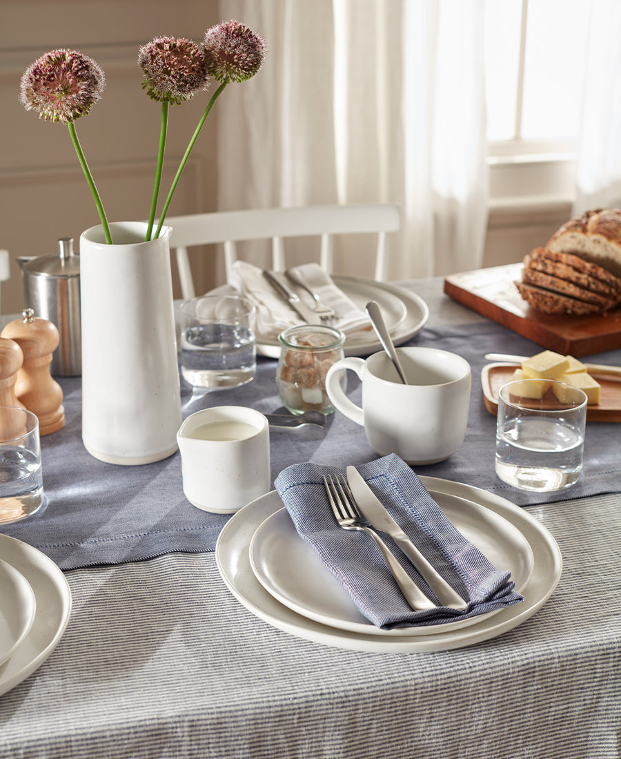 A table is laid for breakfast with blue and white linen table linens and napkins.