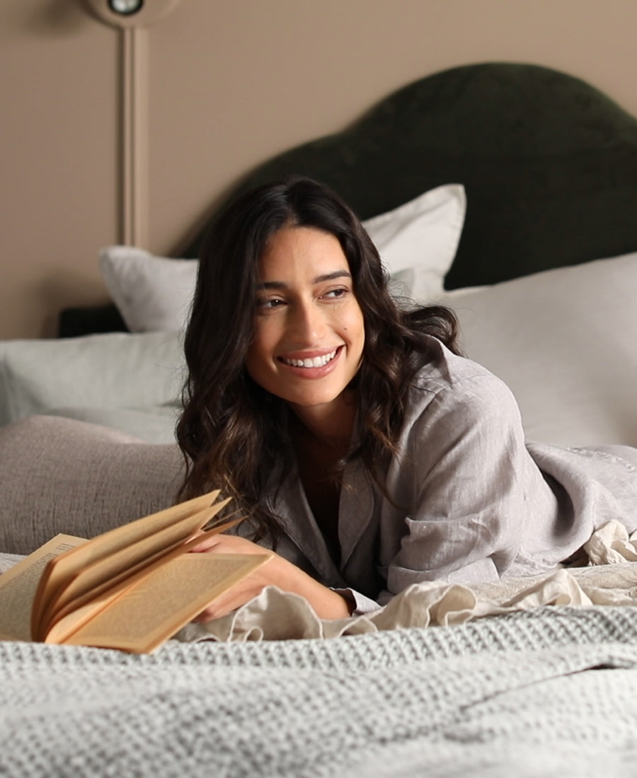 A shot of a model reading a book on a bed.