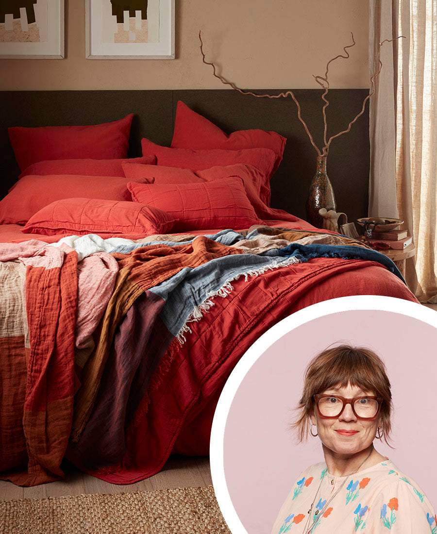 A red bed with cosy throws and cushions.