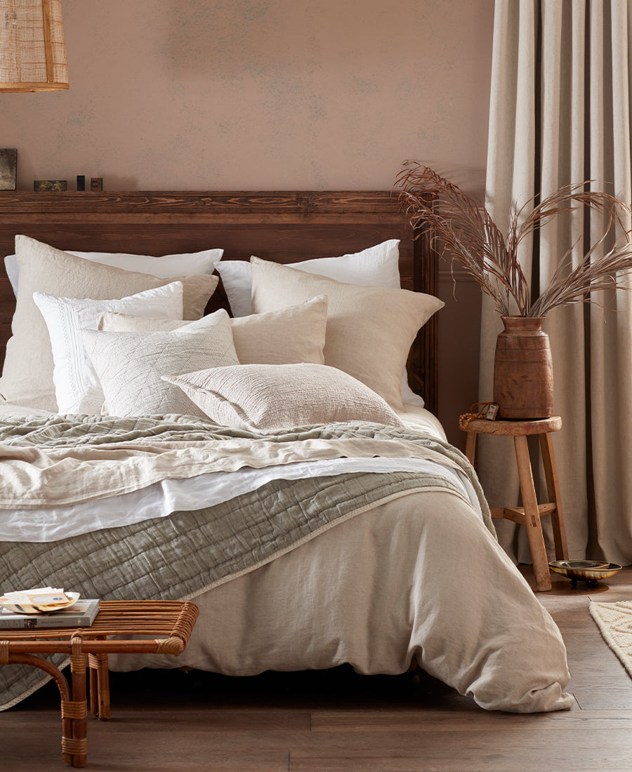 Natural linen bedding is layered with throws and cushions