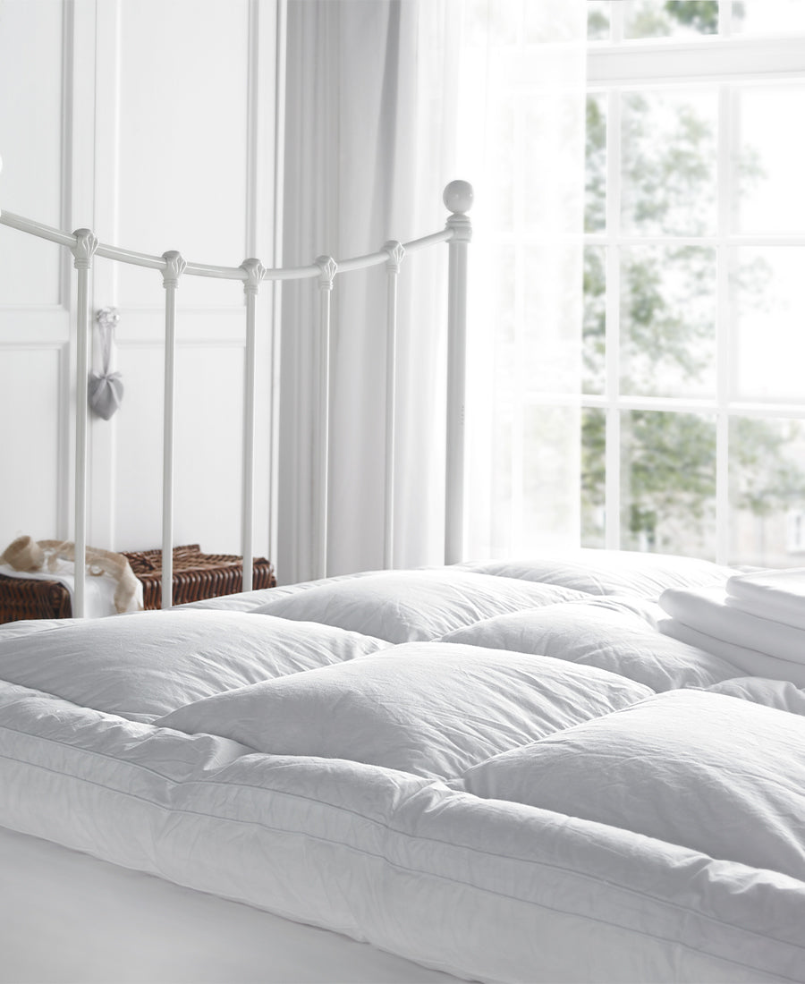 Fluffy pillows and a mattress protector on a bed.